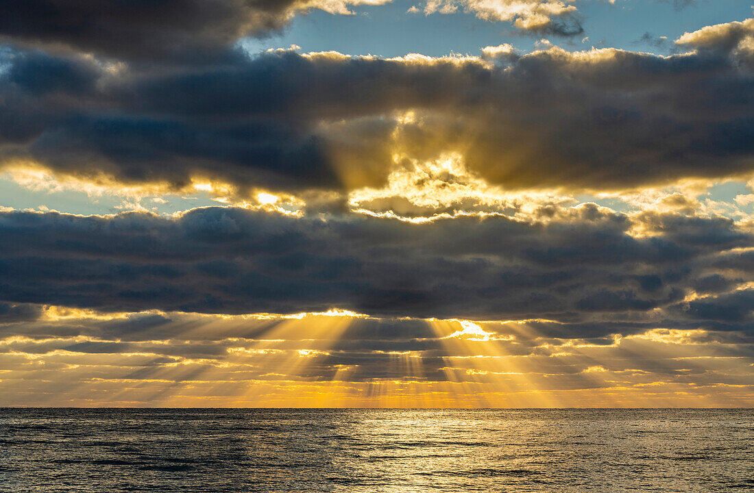 Sonnenstrahlen und goldene Wolken über dem Meer bei Sonnenaufgang