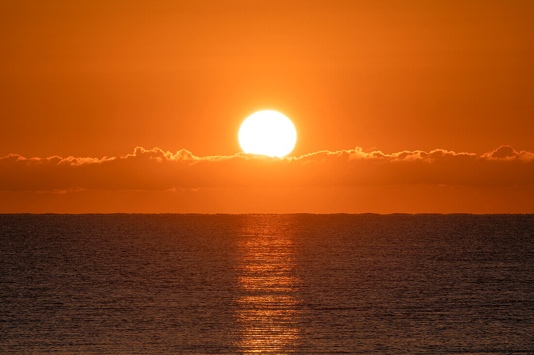 Flammender Sonnenaufgang im orangefarbenen Himmel über dem Ozean