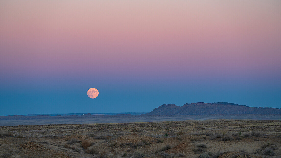 USA, New Mexico, Shiprock, Full moon rising over Navajo Nation desert landscape