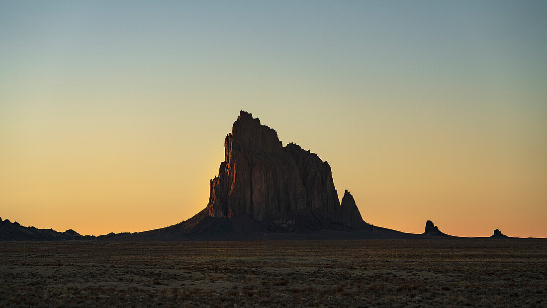 USA, New Mexico, Wüstenlandschaft mit Ship Rock bei Sonnenuntergang