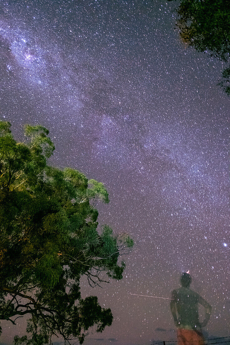Silhouette eines Mannes mit Blick auf die Milchstraße am Nachthimmel