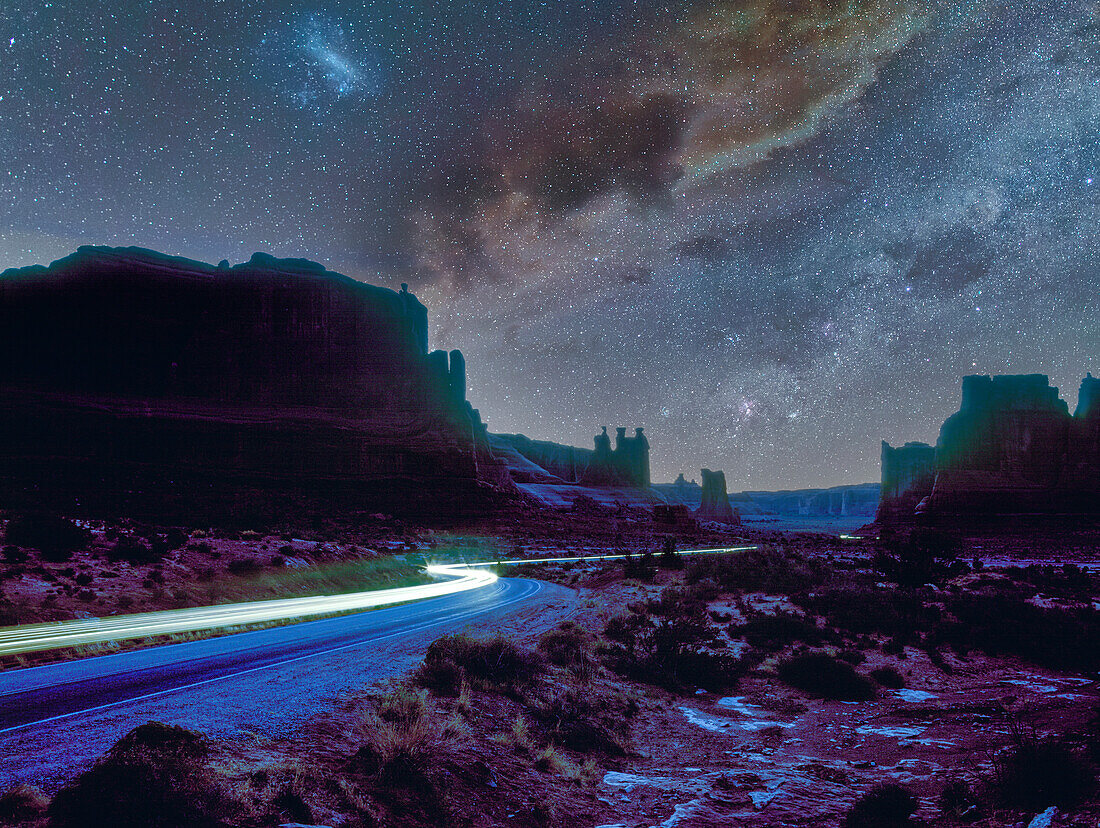 USA, Arizona, Monument Valley Tribal Park, Autos leuchten nachts auf der unbefestigten Straße im Monument Valley