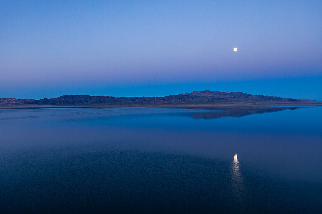 USA, Nevada, Hawthorne, Calm Walker Lake reflecting Moon at dusk