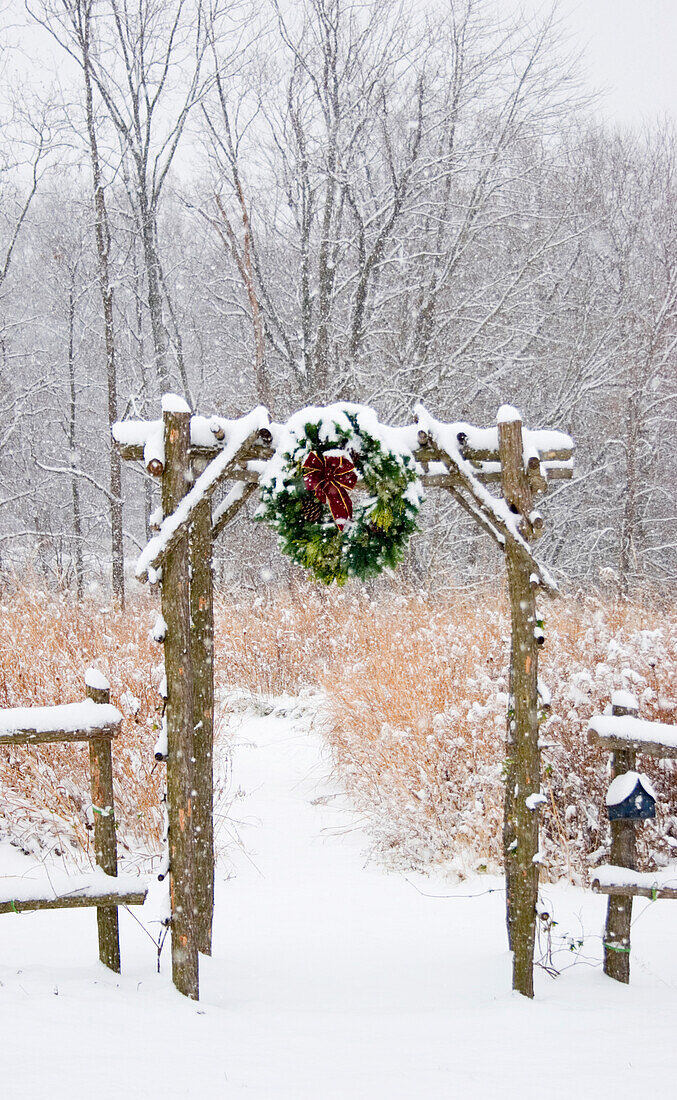 Rustikaler Zaun und Laube mit Weihnachtskranz in der Nähe der Prärie im Winter, Marion County, Illinois
