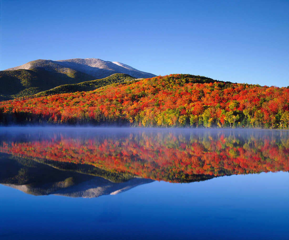 USA, New York, Adirondack Mountains. Snowy Algonquin Peak and autumn colors reflecting in Heart Lake ()
