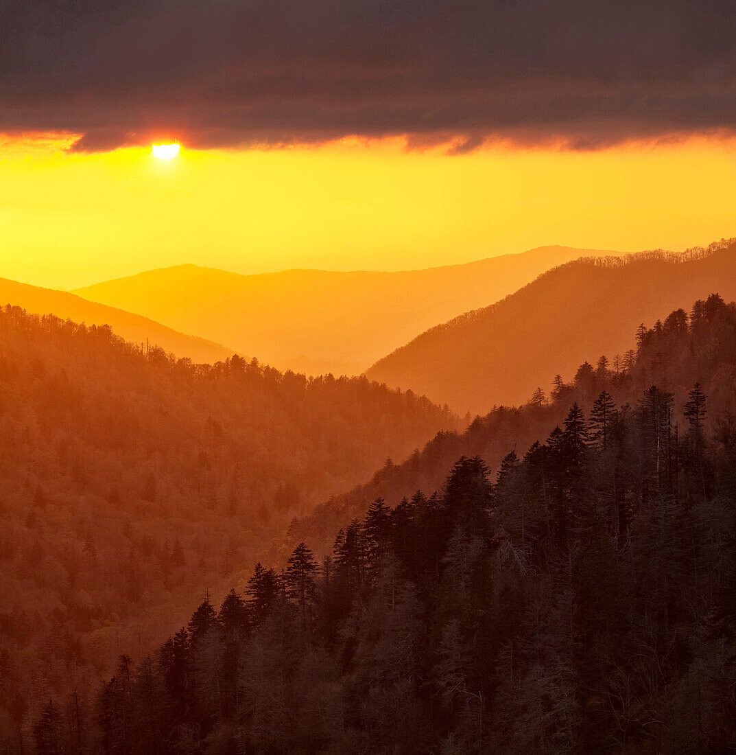 USA, Tennessee, Great-Smoky-Mountains-Nationalpark. Das von Wolken reflektierte Sonnenuntergangslicht erfüllt das Tal mit warmem Licht