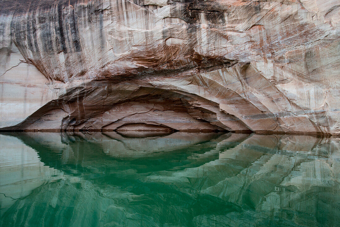 USA, Utah, Glen Canyon National Recreation Area. Bogen in der Schluchtwand mit Reflexion des abstrakten Designs auf dem Wasser des Lake Powell