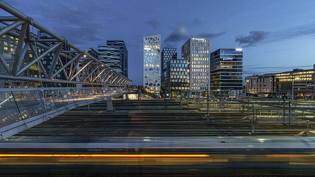 Ausblick vom Bahnhof auf die beleuchtete Skyline des Barcode Viertel in Oslo, Norwegen.