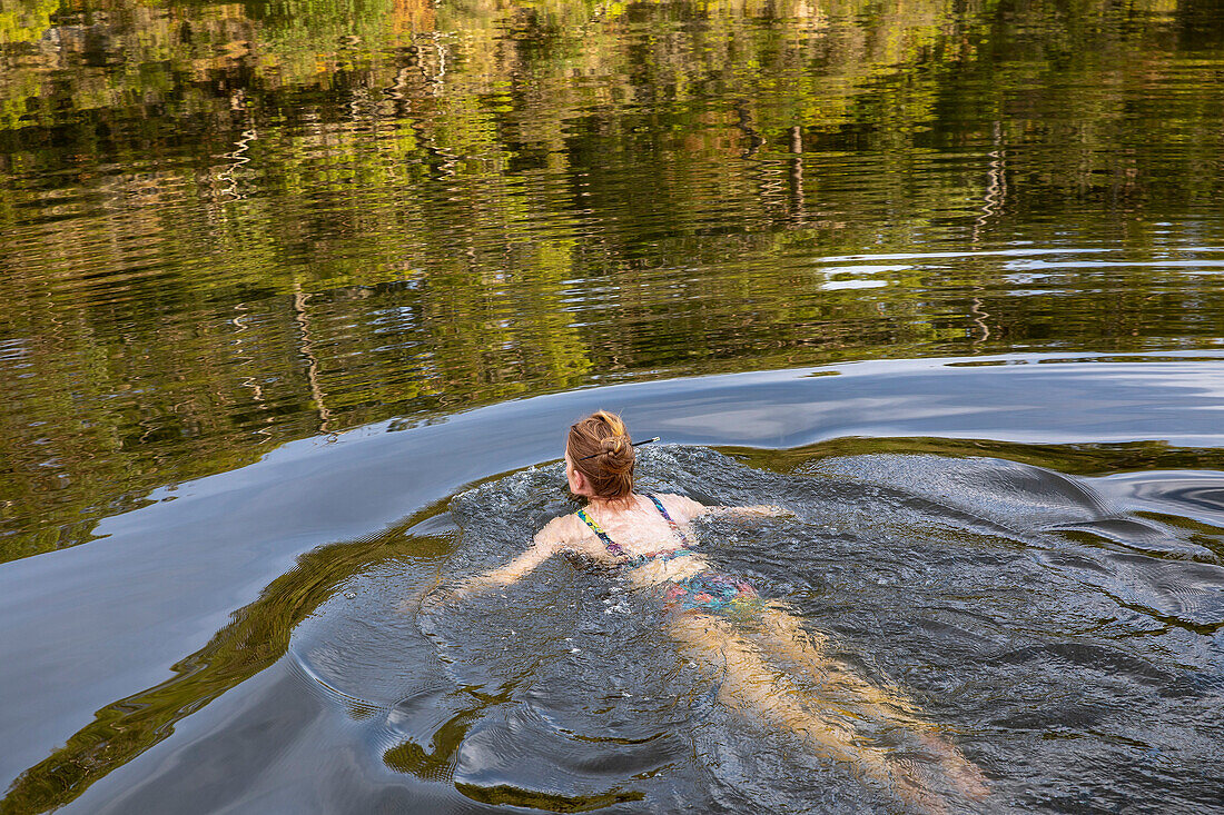 Carefree woman swimming in tranquil summer river