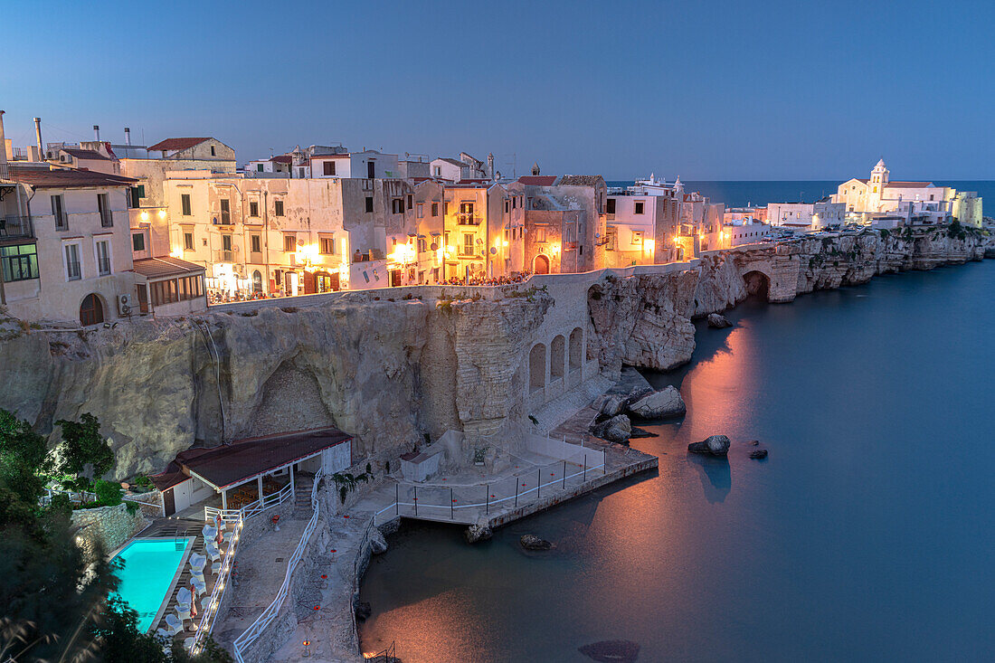 Beleuchteter Pool des Luxusresorts am Meer in der Abenddämmerung in der Altstadt von Vieste, Provinz Foggia, Gargano, Apulien, Italien, Europa