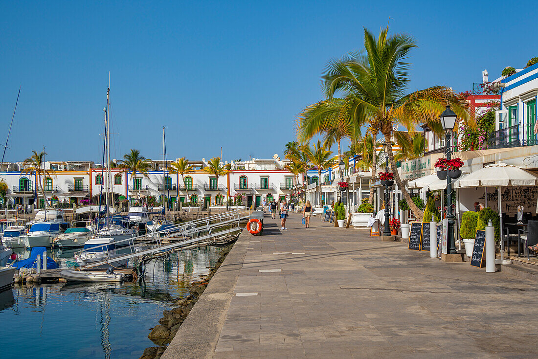 Blick auf Boote und farbenfrohe Gebäude entlang der Promenade in der Altstadt, Puerto de Mogan, Gran Canaria, Kanarische Inseln, Spanien, Atlantik, Europa