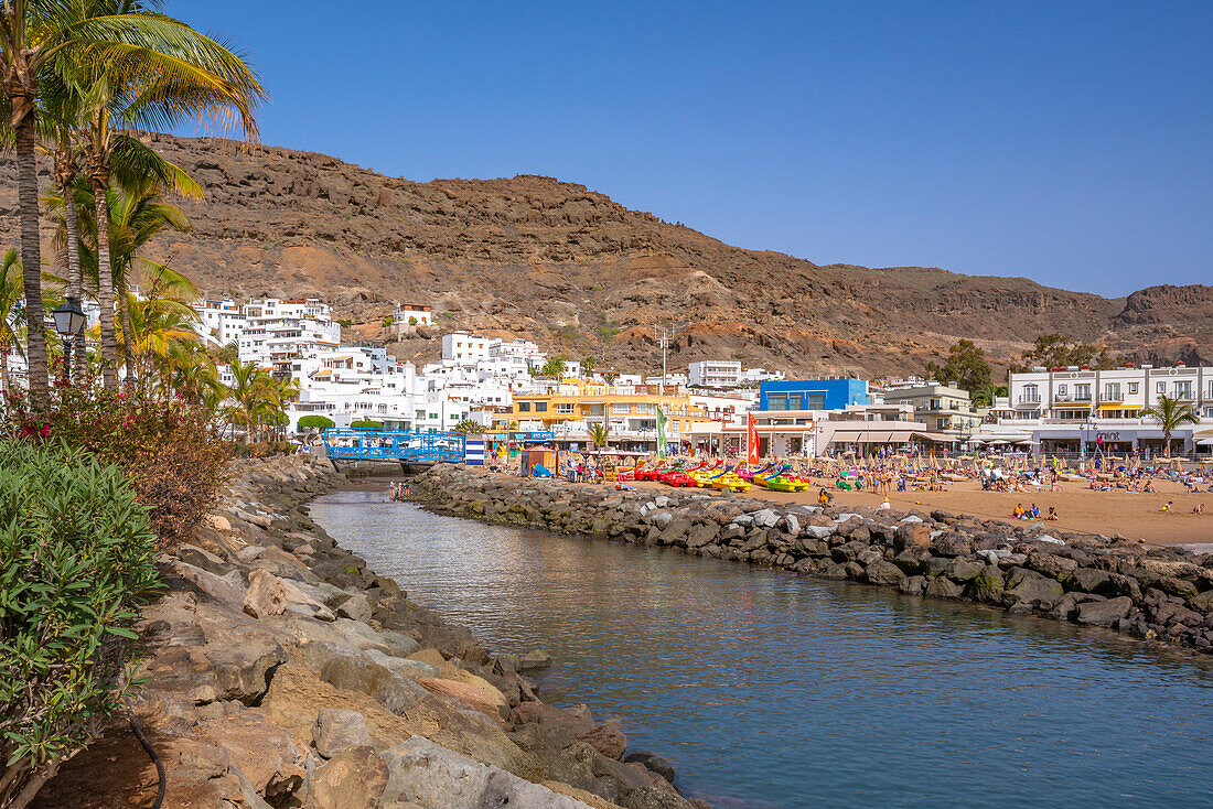 Blick auf Strand und bunte Gebäude entlang der Promenade in der Altstadt, Playa de Mogan, Gran Canaria, Kanarische Inseln, Spanien, Atlantik, Europa