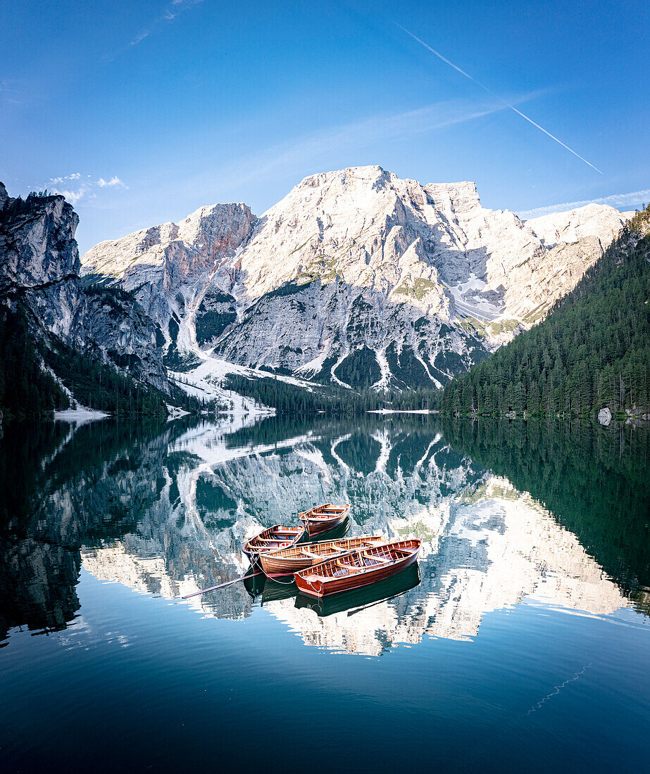 Boats moored in Lake Braies (Pragser Wildsee) with mountains reflected in water at sunrise, Dolomites, South Tyrol, Italy, Europe