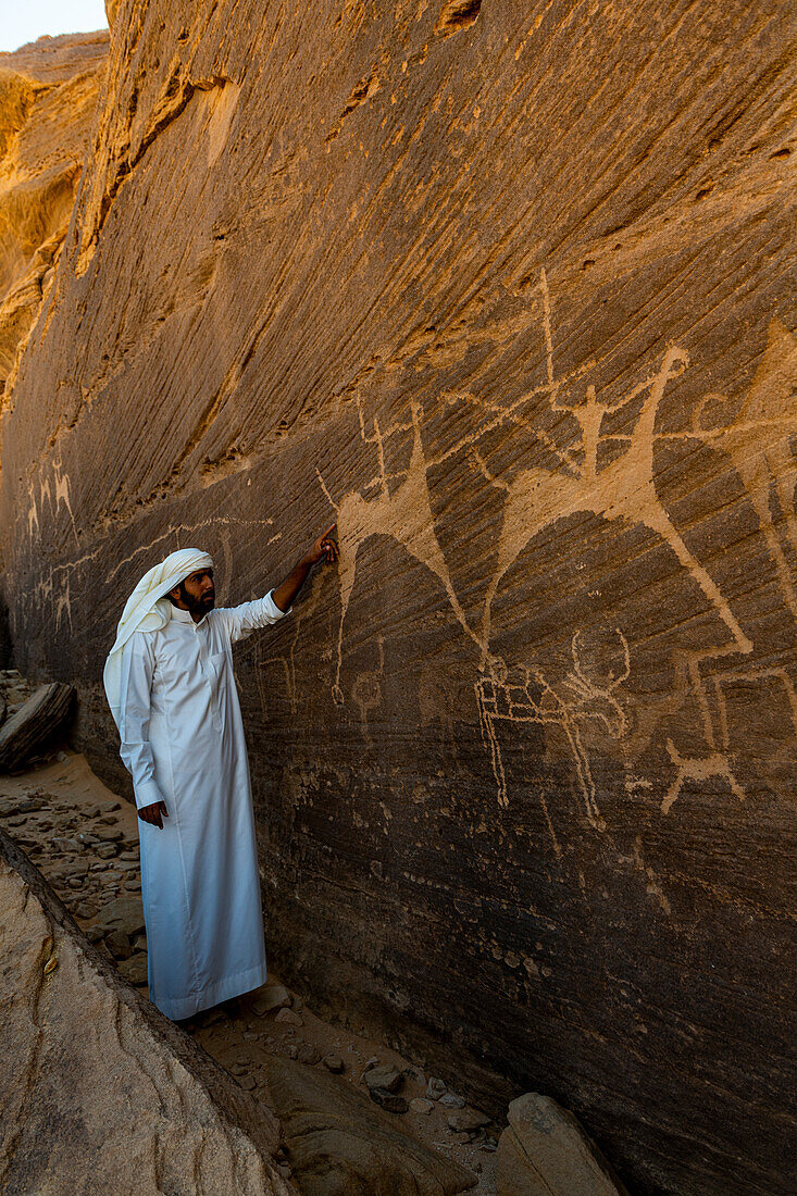 Mann zeigt auf Felszeichnungen, Felszeichnungen und Inschriften von Bir Hima, UNESCO-Weltkulturerbe, Najran, Königreich Saudi-Arabien, Naher Osten