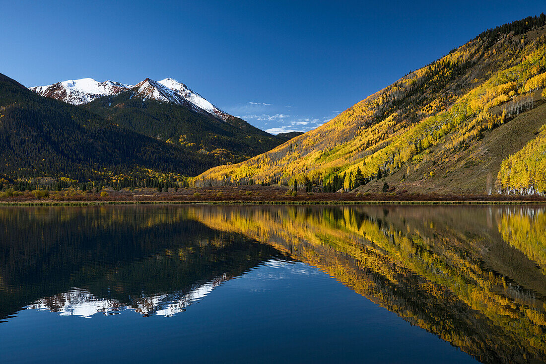 Red Mountain and autumn aspen trees reflected on Crystal Lake at sunrise, near Ouray, Colorado