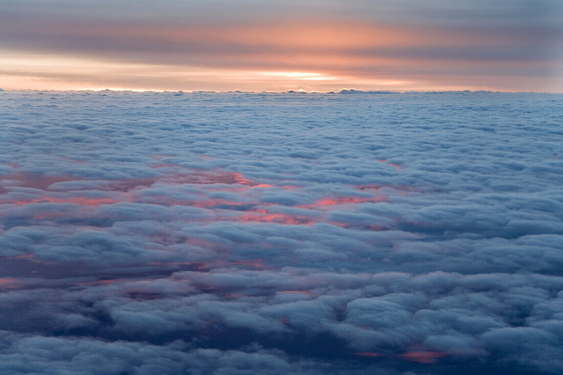 Sunrise from an airliner looking down at clouds.