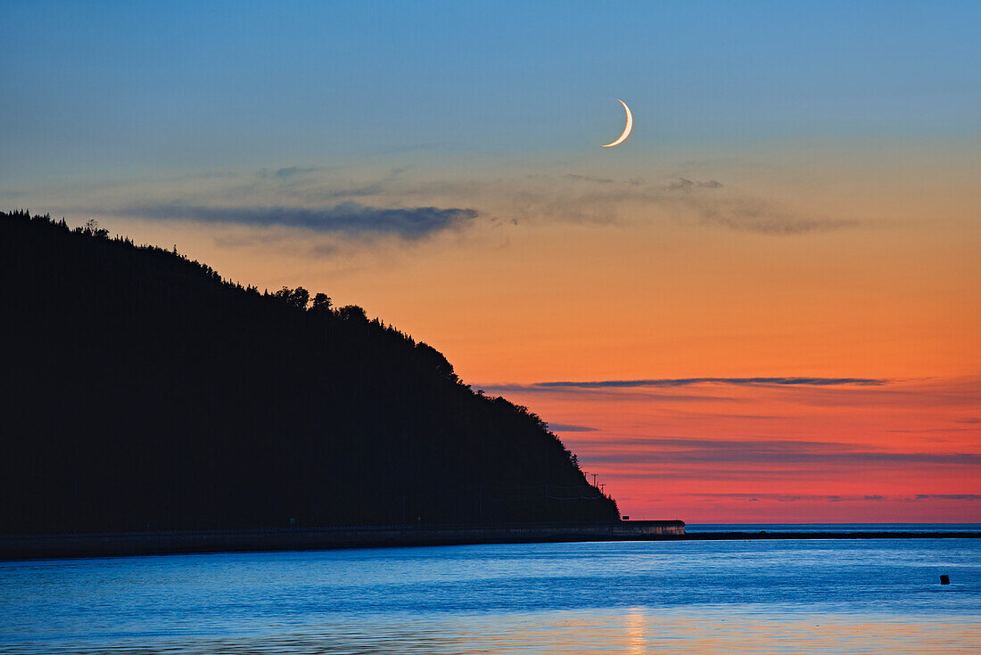 Kanada, Québec, Mont-Louis. Mondsichel-Sonnenaufgang über dem Golf von St. Lawrence.