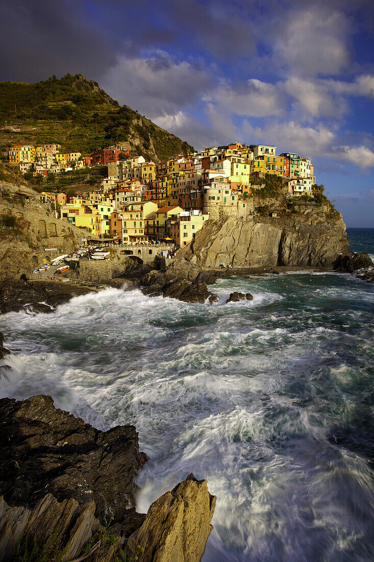 Swirling ocean at the foot of medieval town of Manarola in The Cinque Terre, Liguria Italy