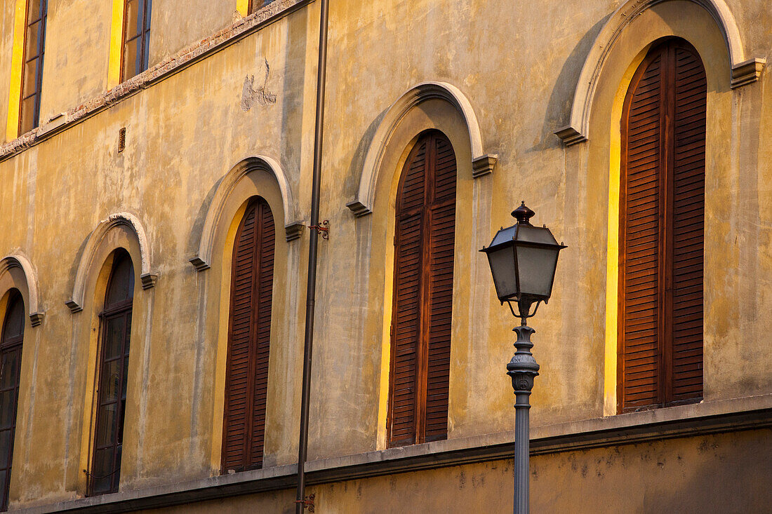 Italien, Toskana, Lucca. Straßenlaterne und gewölbte Fenster mit hölzernen Fensterläden.