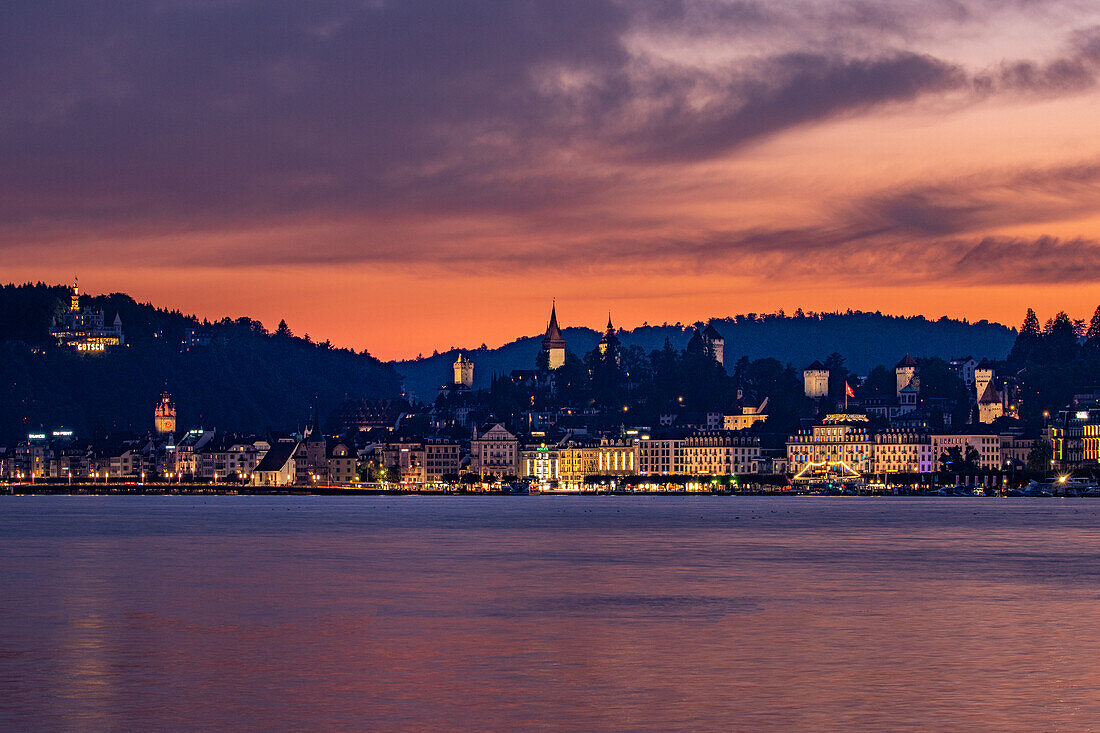 View over Lake Lucerne to illuminated Lucerne with red sky