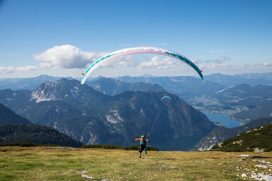 Europe, Austria, Dachstein, Paragliders as they prepare to take off above Lake Hallstatt and the surrounding mountains, all of which is part of the Salzkammergut Cultural Landscape, UNESCO World Heritage Site