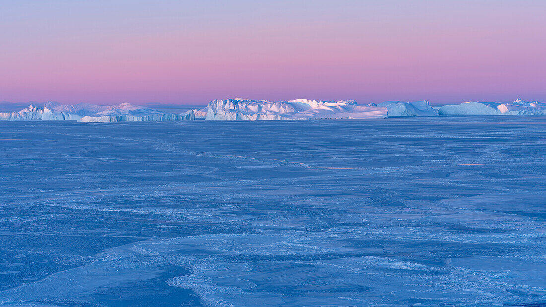 Sonnenaufgang im Winter am Ilulissat-Fjord in der Diskobucht in Westgrönland, der Fjord ist Teil des UNESCO-Weltkulturerbes. Grönland, Dänemark.