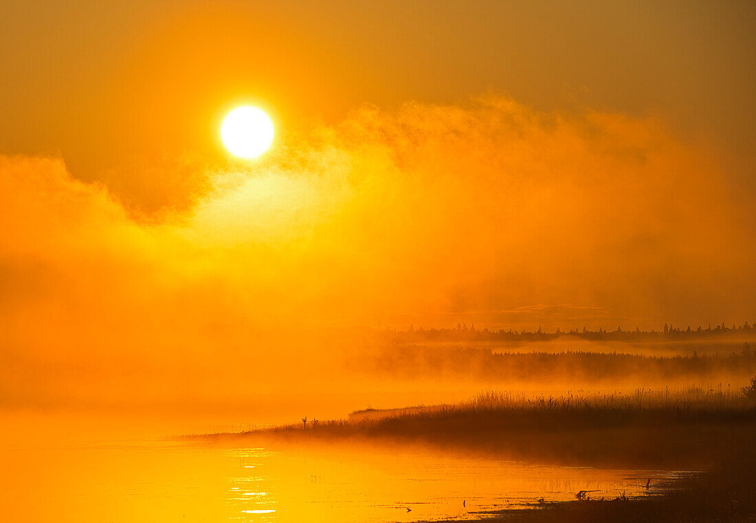 Canada, Manitoba, Riding Mountain National Park. Fog rising above Whirlpool Lake at sunrise.