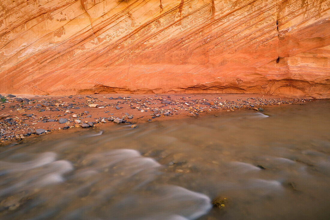 USA, Utah. Capitol Reef National Park, Fremont River und farbenfrohe, erodierte Sandsteinmauer.