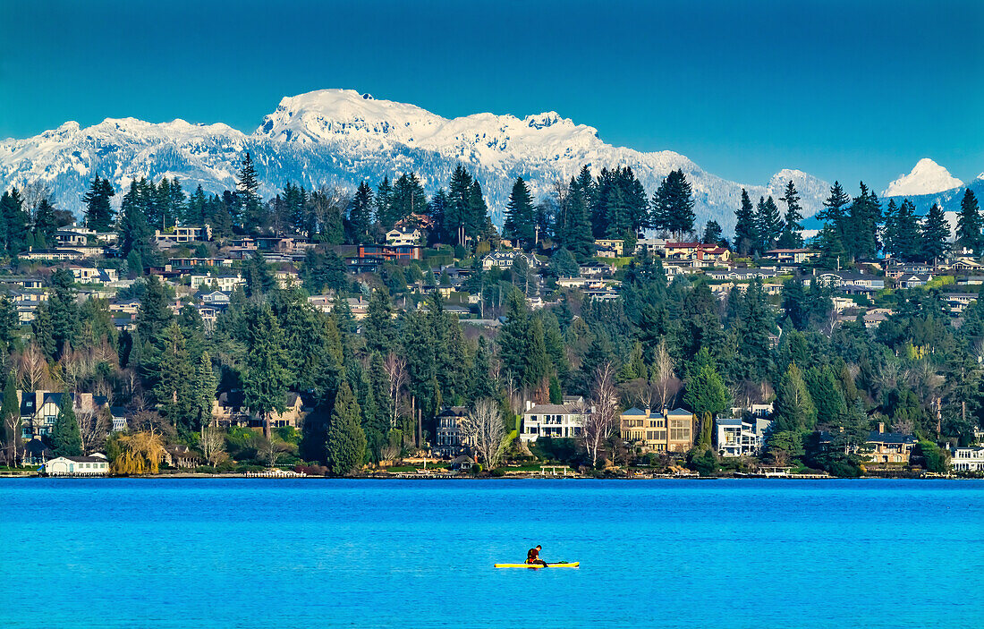 Gelbes Kanu und Häuser, Lake Washington und schneebedeckte Cascade Mountains, Bellevue, Washington State.
