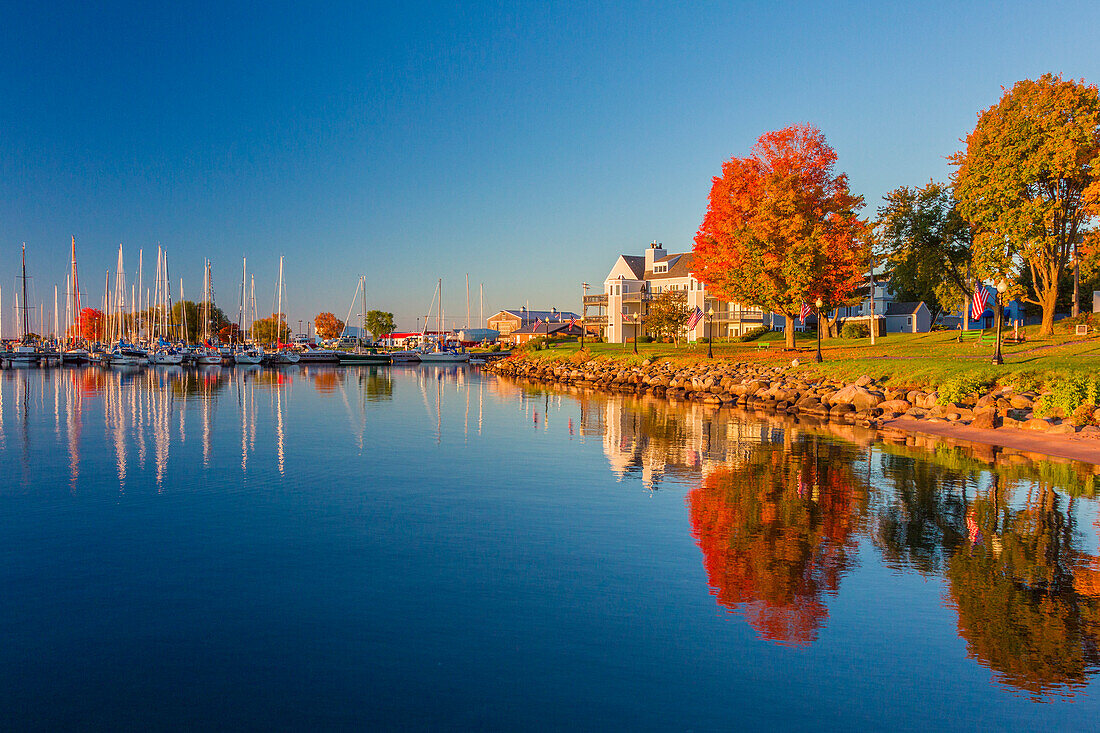USA, Wisconsin. Fall colors reflected on the still waters of the harbor in Bayfield on Lake Superior.