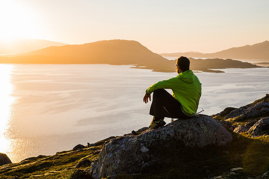 Norwegen, Lofoten, Mann im Sonnenuntergang über dem Fjord