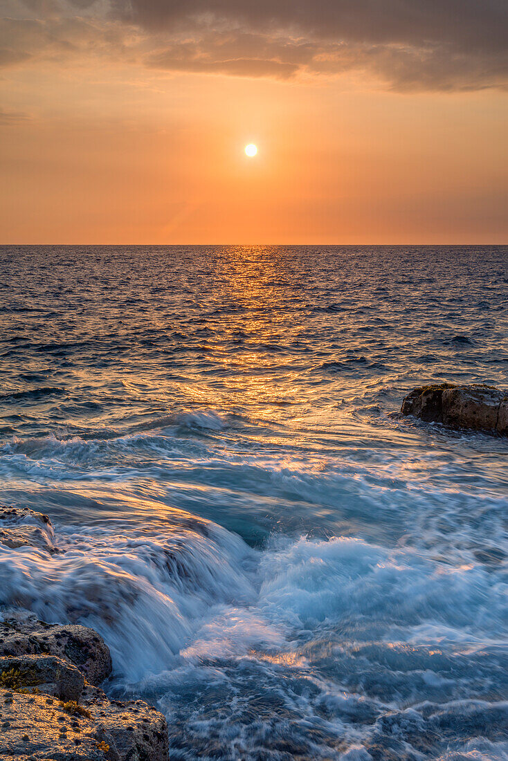 USA, Hawaii, Big Island of Hawaii. Wawaloli Beach Park, Late afternoon sun highlights ocean waves and rocky shoreline.