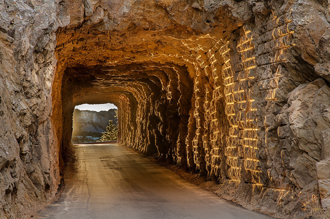 Tunnel on Iron Mountain Road lit by setting sun with view of Mount Rushmore near Keystone, South Dakota, USA