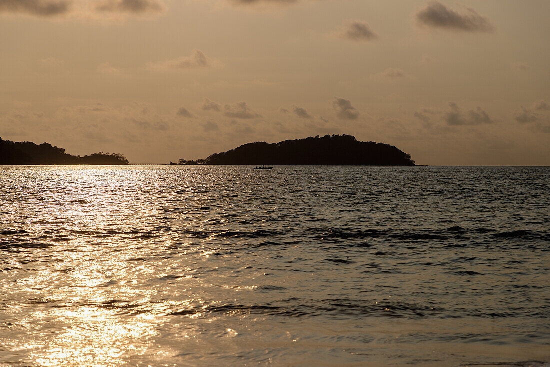 Bom Bom Island und Fischerboot nach Sonnenuntergang, Ausblick von Praia Cajú auf der Insel Príncipe in Westafrika, Sao Tomé e Príncipe