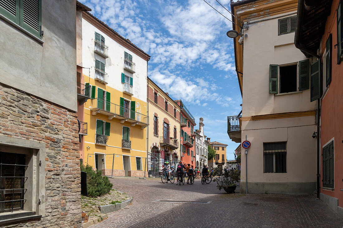 Cyclists in Piazza Italia in the historic center of Neive, Cuneo, Langhe, Piedmont.