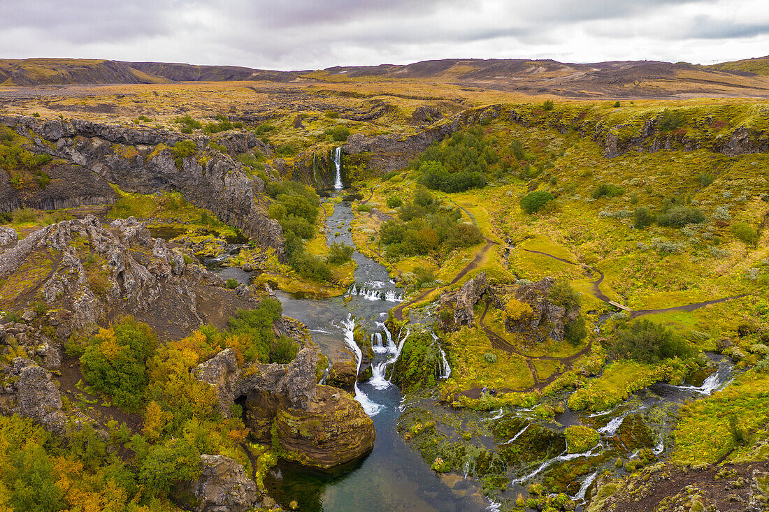 Europa, Island. Panoramablick aus der Luft auf die Gjain-Wasserfälle in einem ruhigen und malerischen Tal im südlichen Hochland.