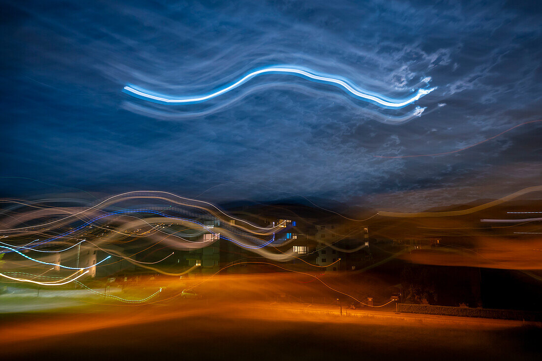 Long Exposure on a City with Light Trails and Moon and Sky With Clouds in Caslano, Ticino, Switzerland.