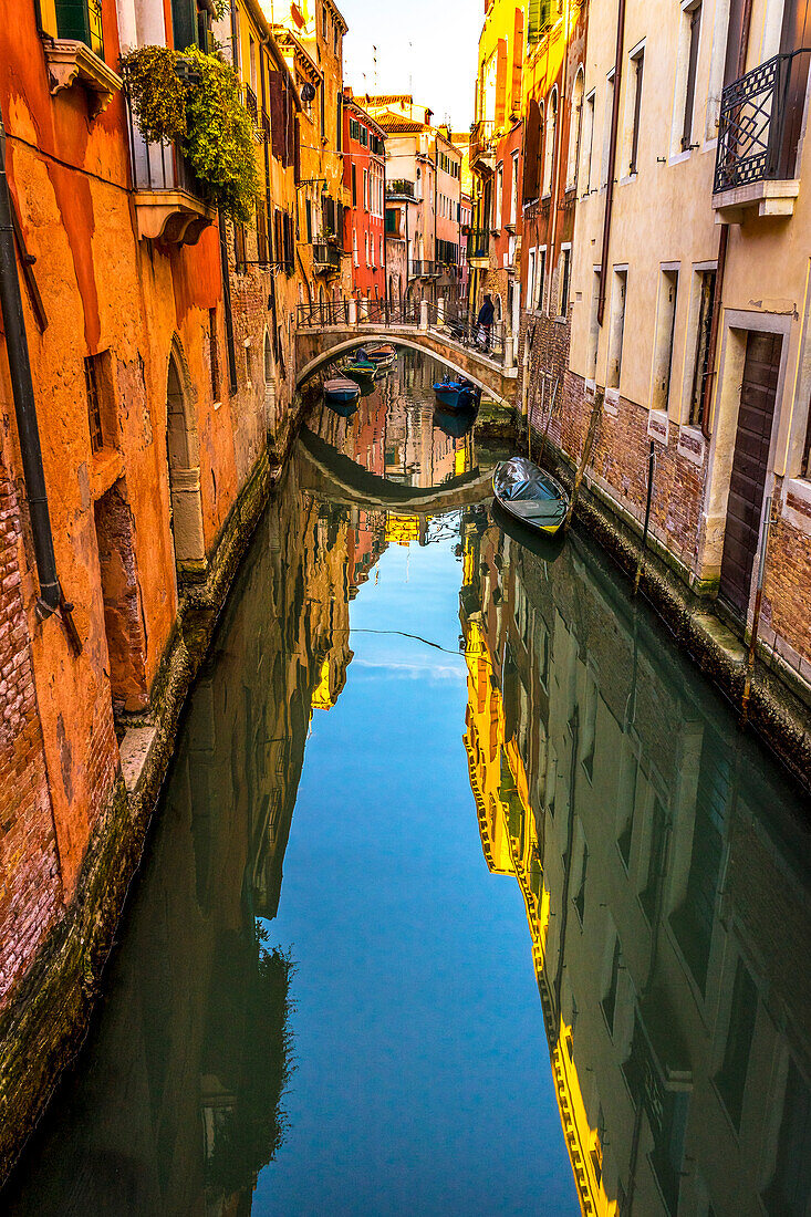 Ein farbenfroher kleiner Kanal und eine Brücke schaffen eine schöne Reflexion in Venedig, Italien.