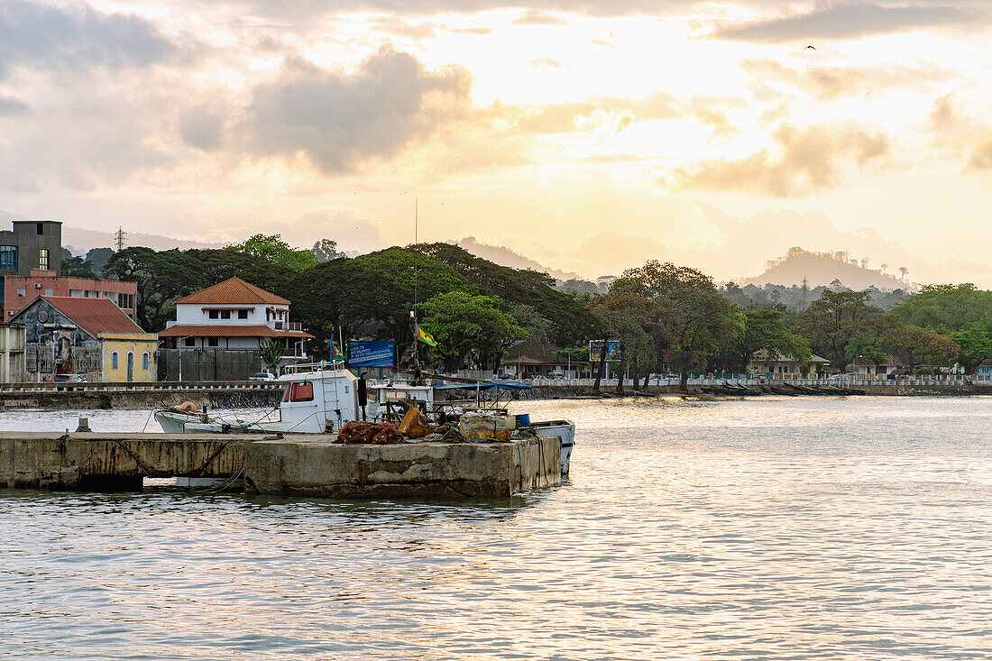 Port pier and fishing boat under a dramatic evening sky at Ana Chavez Bay in Sao Tome on Sao Tome Island in West Africa