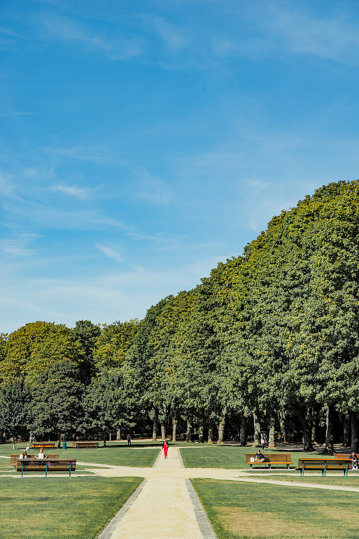 Woman in red walking through the park du Cinquantenaire in Brussels, Belgium