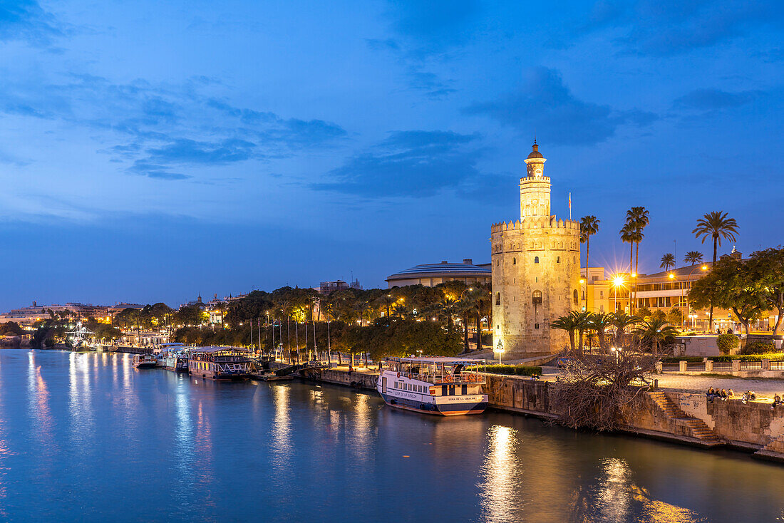 On the banks of the Guadalquivir River with the historic Torre del Oro tower at dusk, Seville, Andalusia, Spain