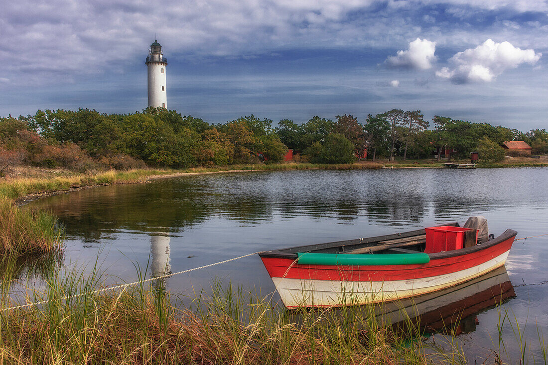 Kleines Fischerboot liegt am Ufer. Leuchtturm im Hintergrund. Boot und Turm spiegeln sich. Ölands Norra Udde, Öland, Langer Erik, Schweden.