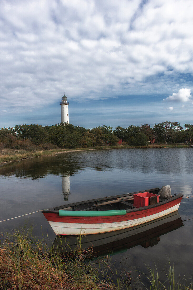 Kleines Fischerboot liegt am Ufer. Leuchtturm im Hintergrund. Boot und Turm spiegeln sich. Ölands Norra Udde, Öland, Langer Erik, Schweden.