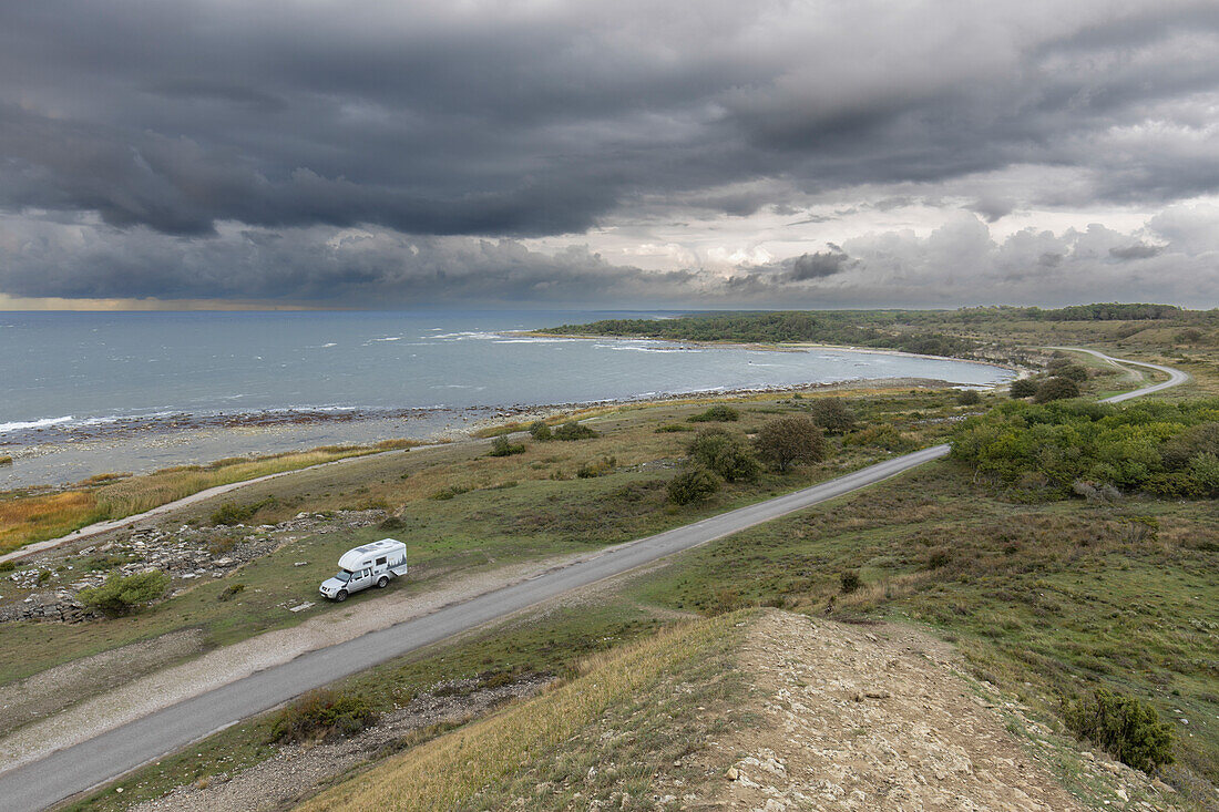 Einzelnes Wohnmobil steht an kleiner Straße am Meer. Kurz vor Sonnenuntergang. Burgsvik, Gotland, Schweden.