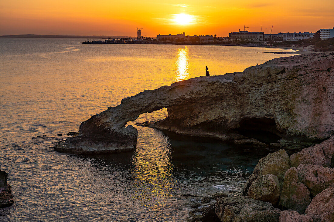 young woman posing on the natural stone bridge Bridge of Love at sunset, Ayia Napa, Cyprus, Europe