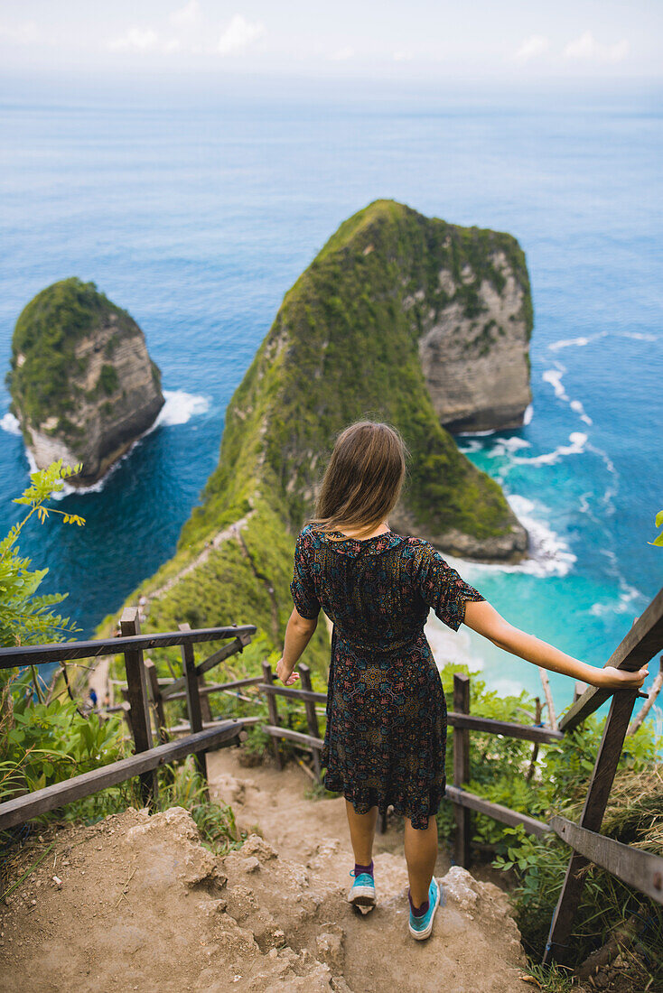 Woman on hillside steps above Kelingking Beach in Nusa Penida, Indonesia