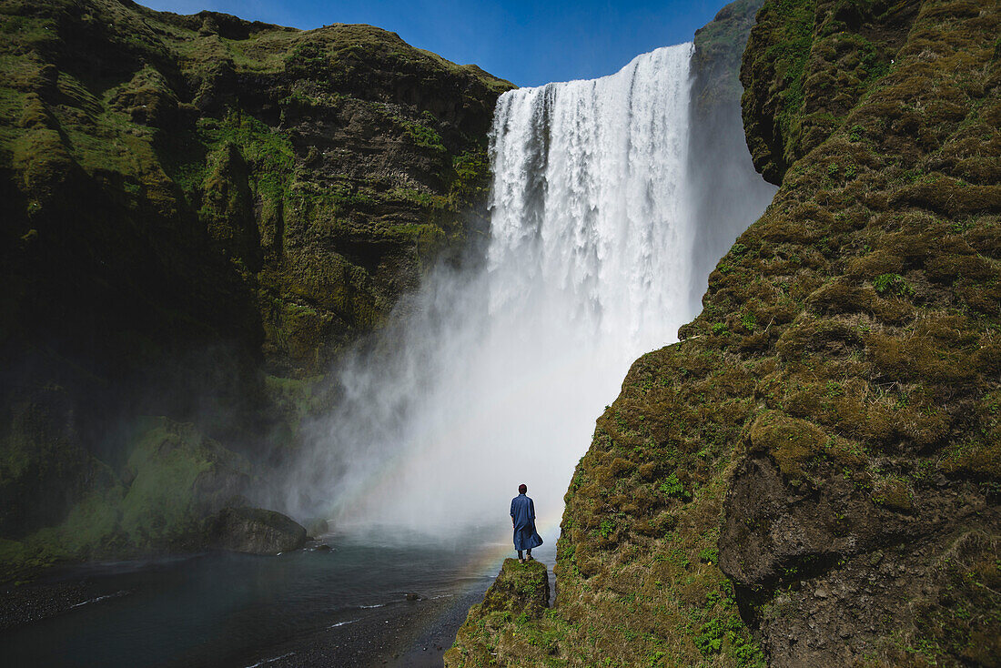 Mann, der am Skogafoss-Wasserfall in Island steht