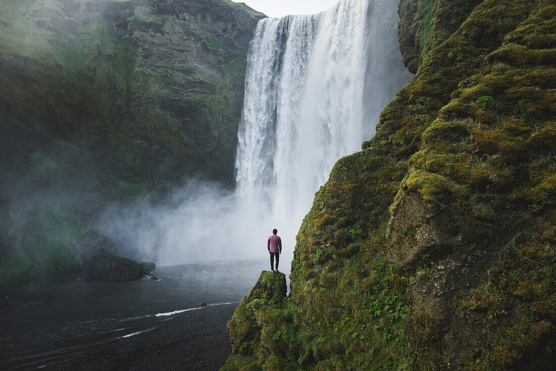 Man standing by Skogafoss waterfall in Iceland