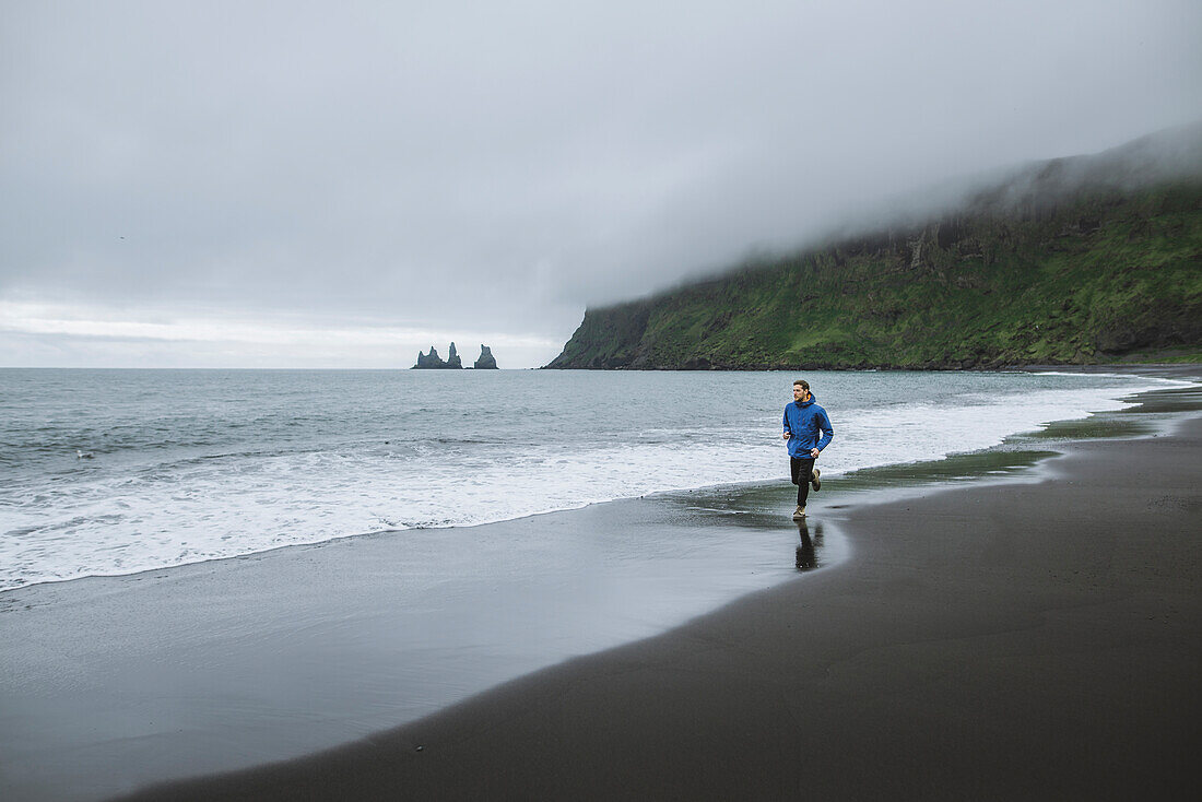 Mann beim Joggen am Strand in Vik, Island