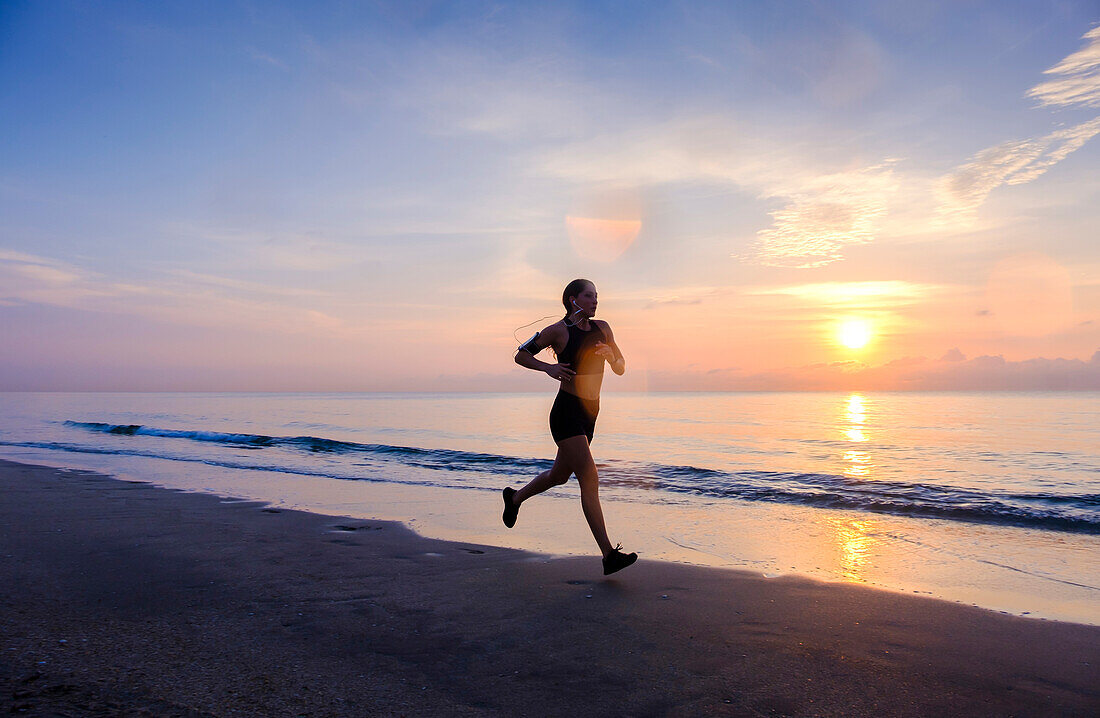 Frau beim Joggen am Strand bei Sonnenuntergang